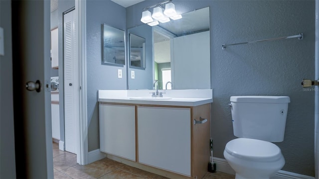 bathroom with vanity, tile patterned flooring, a closet, toilet, and a textured wall