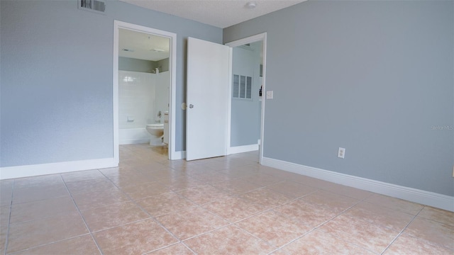 spare room featuring light tile patterned floors, visible vents, baseboards, and a textured ceiling