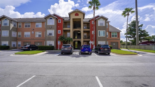 view of building exterior with fence and uncovered parking