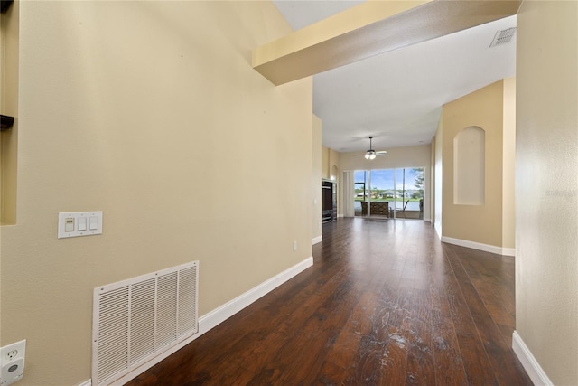 hallway with dark wood-type flooring, visible vents, and baseboards