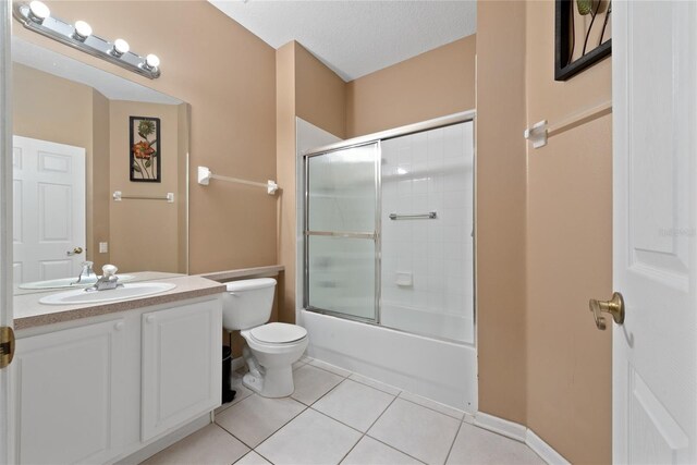 full bathroom with shower / bath combination with glass door, vanity, a textured ceiling, toilet, and tile patterned floors