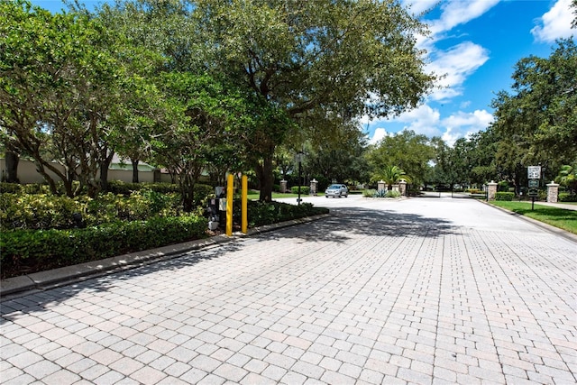 view of road with traffic signs, curbs, and a gated entry