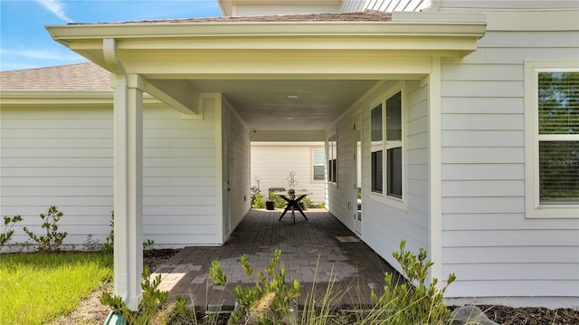 view of exterior entry featuring roof with shingles