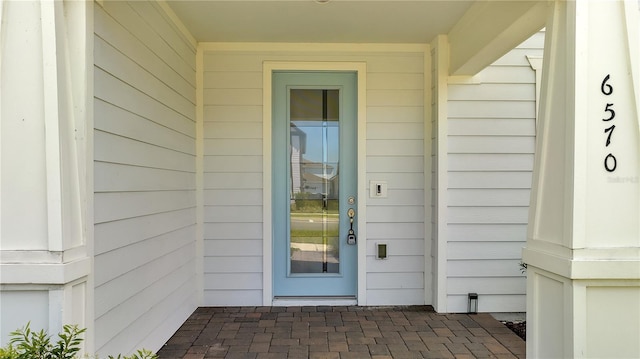 view of exterior entry featuring roof with shingles