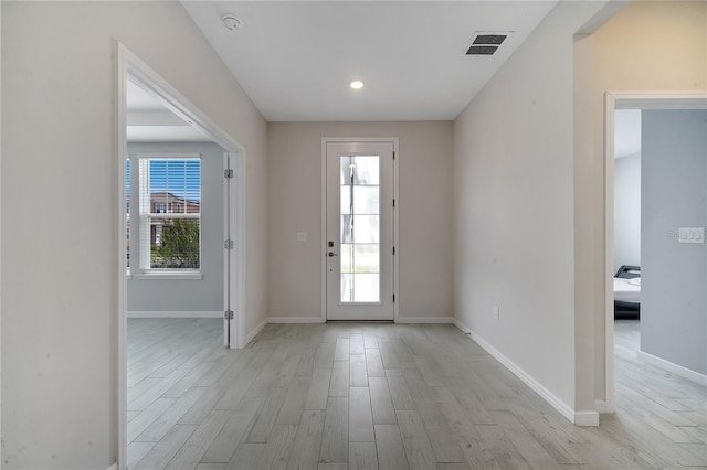 doorway featuring light wood-style flooring, visible vents, and baseboards