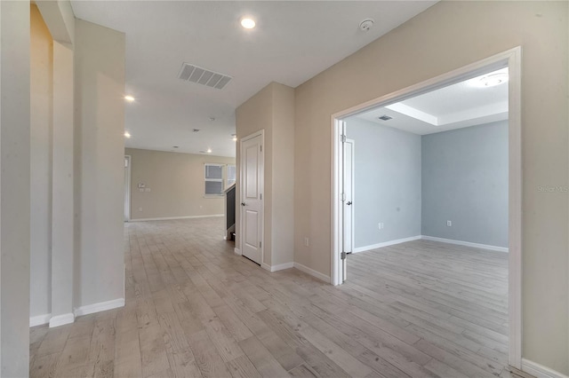 hallway featuring light wood-type flooring, baseboards, visible vents, and recessed lighting