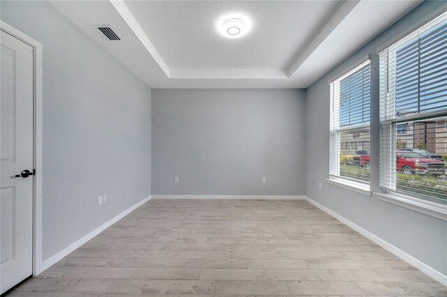 unfurnished room featuring light wood-type flooring and a tray ceiling