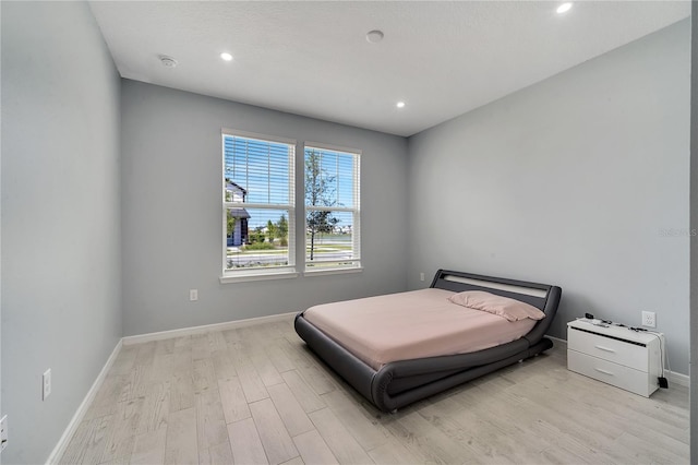 bedroom with baseboards, wood finished floors, and recessed lighting