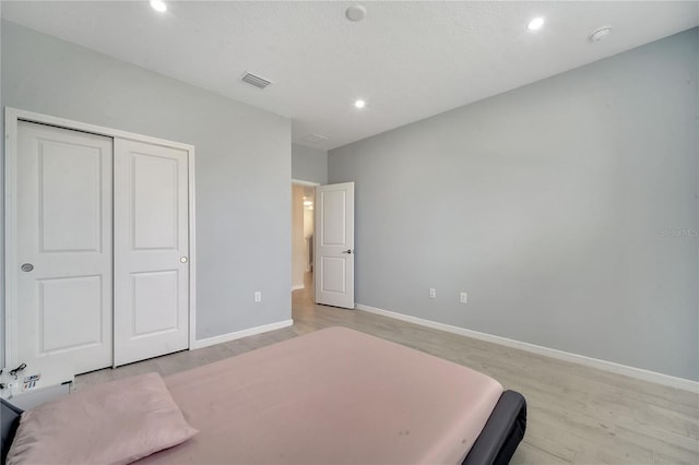 bedroom featuring a closet, light hardwood / wood-style floors, and a textured ceiling