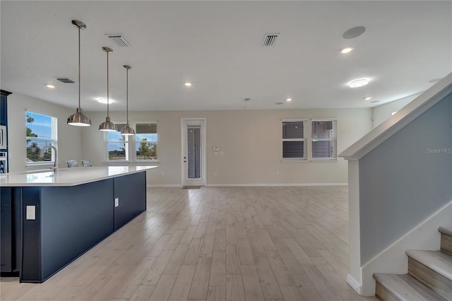 kitchen featuring light wood finished floors, light countertops, visible vents, a sink, and blue cabinets