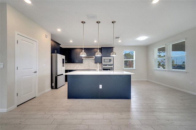 kitchen featuring a center island with sink, light hardwood / wood-style flooring, appliances with stainless steel finishes, and tasteful backsplash