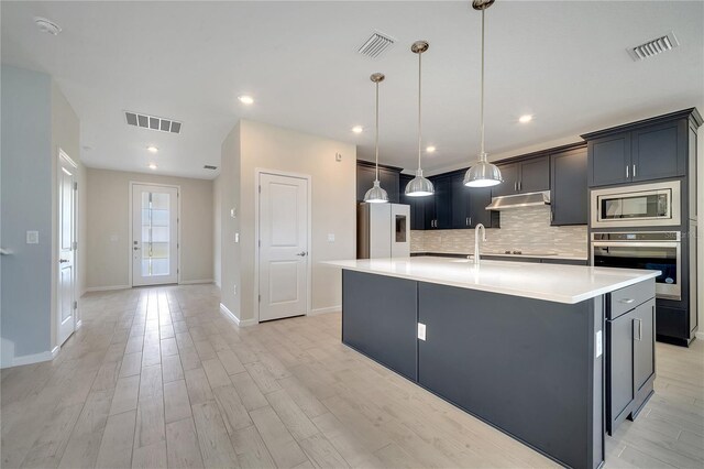 kitchen with hanging light fixtures, tasteful backsplash, stainless steel appliances, and a kitchen island with sink