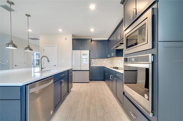 kitchen with stainless steel appliances, light countertops, visible vents, backsplash, and a sink