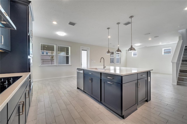 kitchen with a sink, visible vents, light wood-style floors, stainless steel dishwasher, and wall chimney exhaust hood