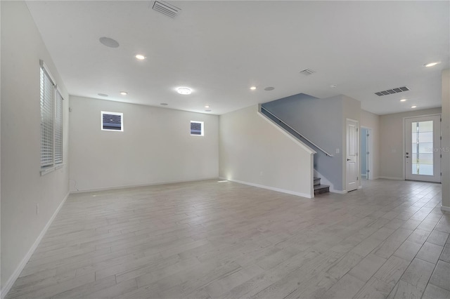 unfurnished room featuring light wood finished floors, stairway, visible vents, and baseboards