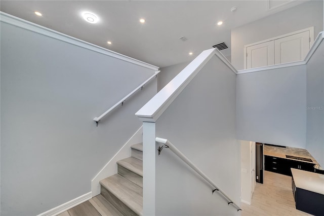 stairway with baseboards, visible vents, wood finished floors, and recessed lighting