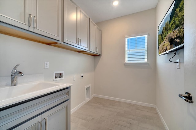 washroom featuring hookup for a washing machine, a sink, baseboards, cabinet space, and electric dryer hookup