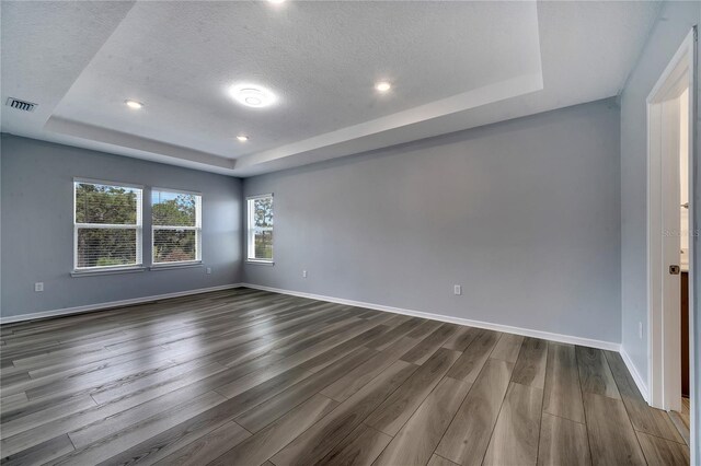 spare room featuring a tray ceiling, a textured ceiling, and wood-type flooring