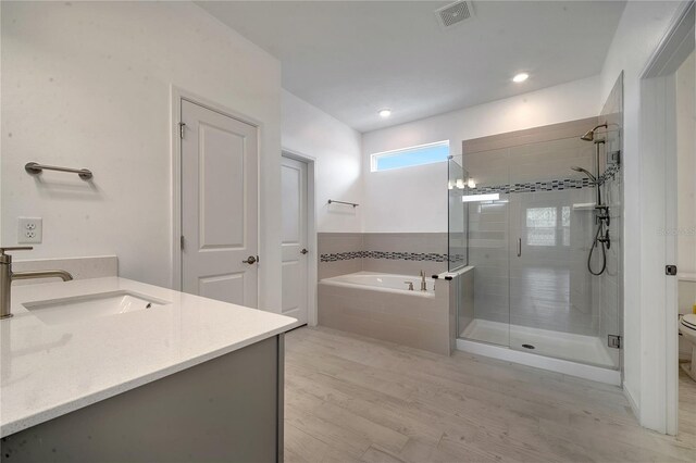 full bathroom featuring wood-type flooring, toilet, independent shower and bath, and vanity