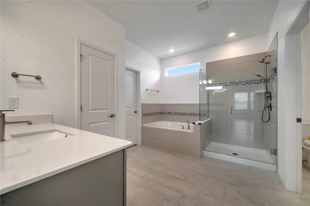 full bath with visible vents, wood finished floors, vanity, a shower stall, and a bath