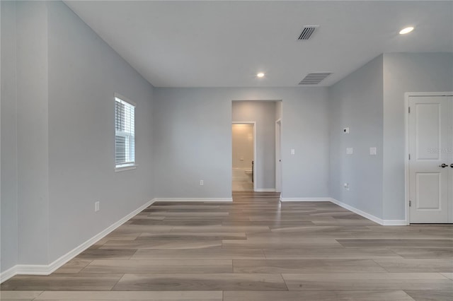 spare room featuring wood finish floors, visible vents, and baseboards