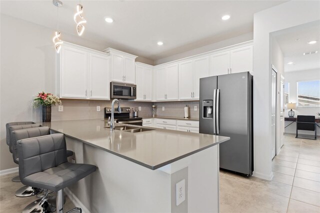 kitchen with a kitchen bar, hanging light fixtures, kitchen peninsula, sink, and stainless steel appliances