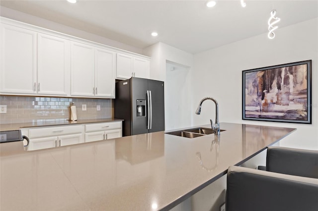 kitchen featuring pendant lighting, white cabinetry, tasteful backsplash, sink, and stainless steel fridge with ice dispenser