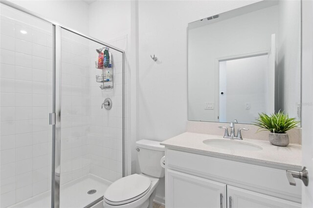 bathroom with a shower with shower door, toilet, and vanity