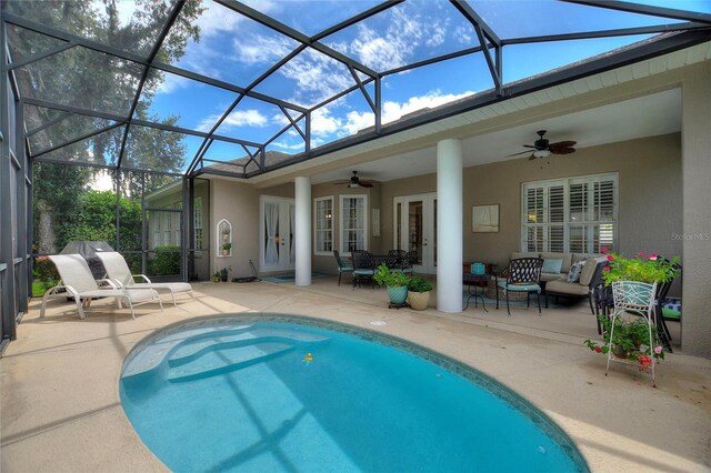 view of swimming pool with a patio area, glass enclosure, french doors, an outdoor hangout area, and ceiling fan