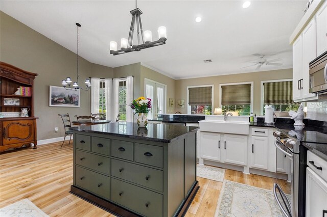 kitchen with ceiling fan with notable chandelier, appliances with stainless steel finishes, white cabinetry, and light hardwood / wood-style flooring