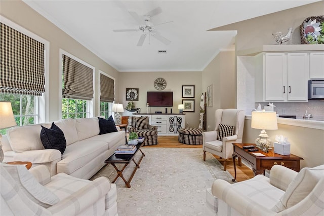 living room featuring ceiling fan, light hardwood / wood-style floors, and crown molding