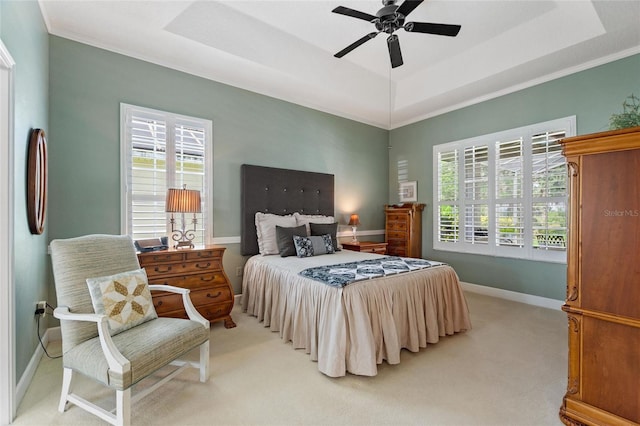 carpeted bedroom with a tray ceiling, ceiling fan, and ornamental molding