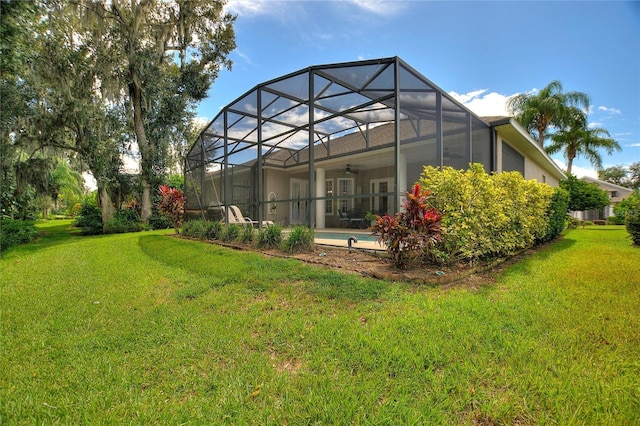 back of property with glass enclosure and a lawn