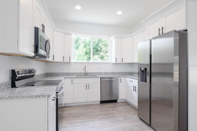 kitchen featuring white cabinetry, light hardwood / wood-style flooring, stainless steel appliances, sink, and light stone countertops