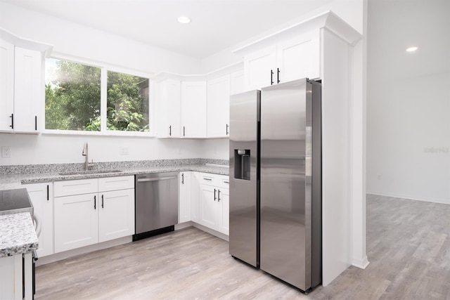 kitchen with light hardwood / wood-style flooring, stainless steel appliances, white cabinetry, and sink