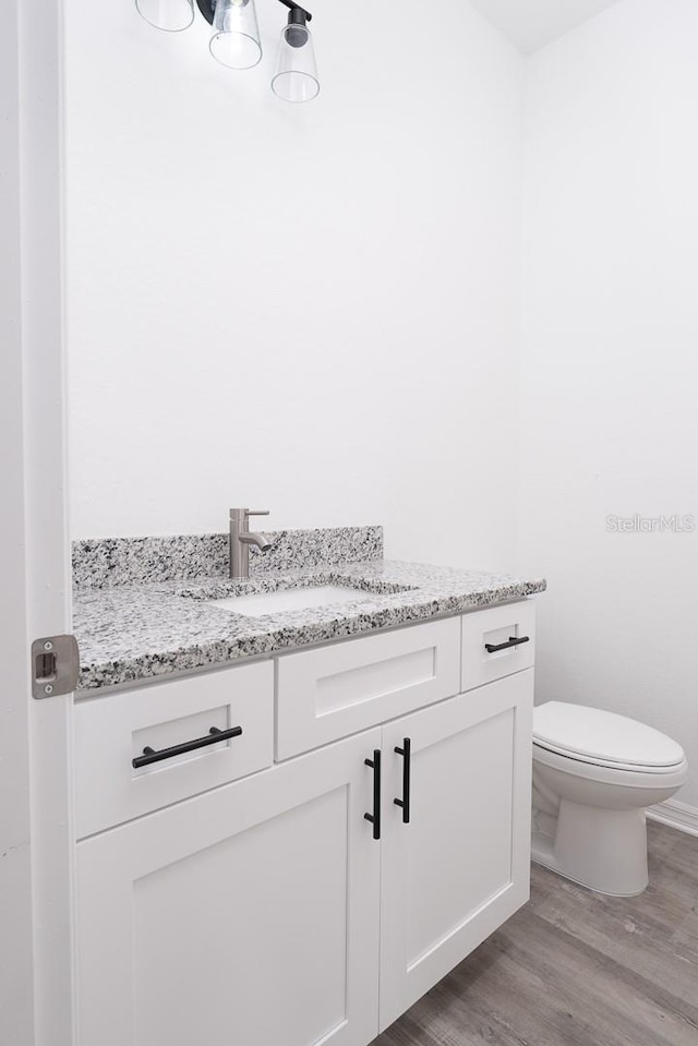 bathroom featuring vanity, toilet, and hardwood / wood-style flooring