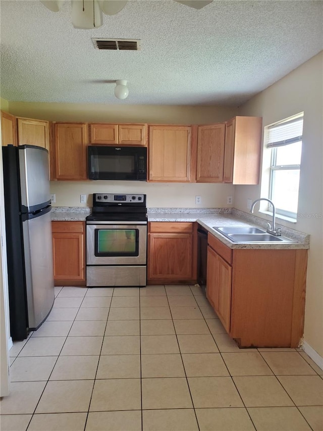 kitchen featuring light tile patterned floors, a textured ceiling, sink, and black appliances