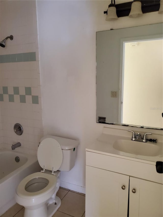 full bathroom with tile patterned flooring, tiled shower / bath combo, vanity, and toilet