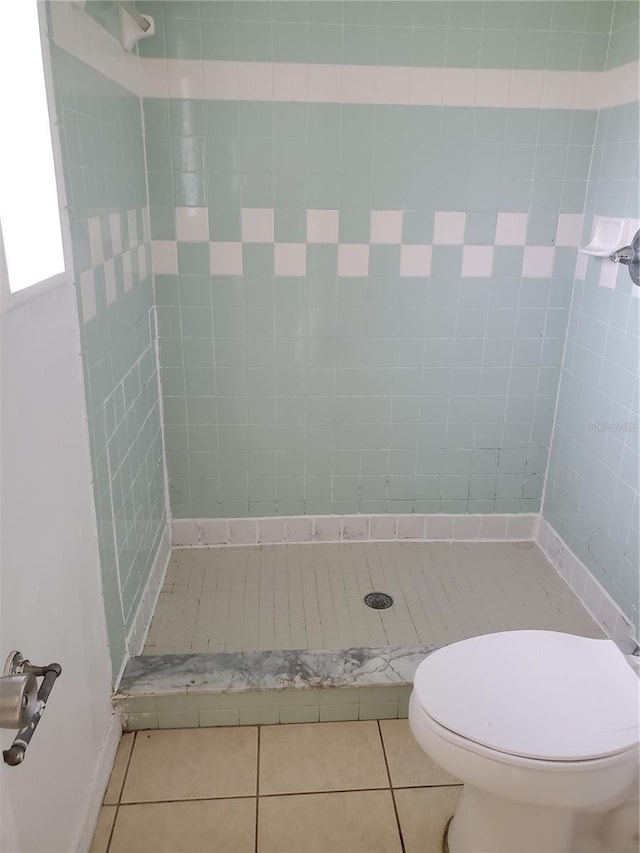 bathroom featuring tile patterned flooring, tiled shower, and toilet