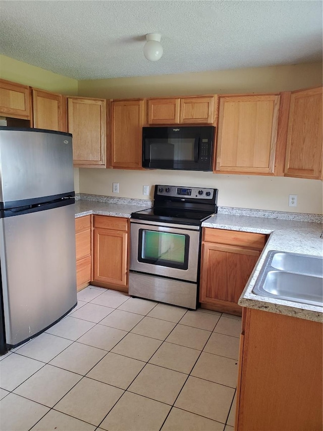 kitchen featuring light tile patterned flooring, appliances with stainless steel finishes, sink, and a textured ceiling