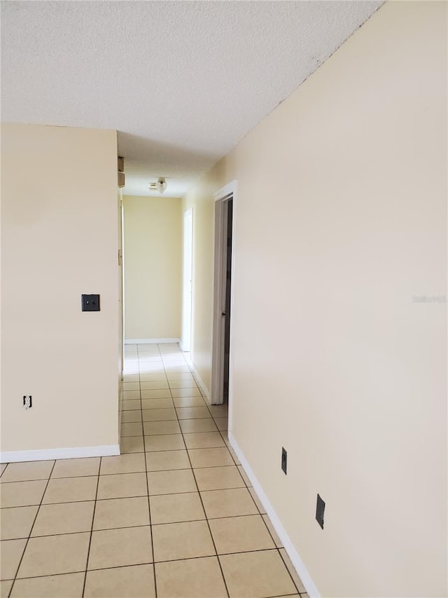 corridor with light tile patterned floors and a textured ceiling