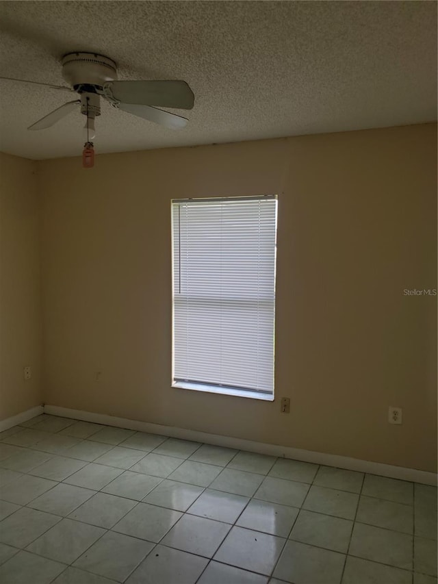 spare room featuring ceiling fan, a textured ceiling, and light tile patterned floors