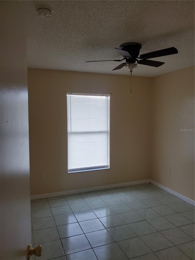 unfurnished room with ceiling fan, light tile patterned floors, and a textured ceiling