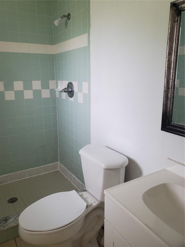 bathroom with vanity, tiled shower, and toilet