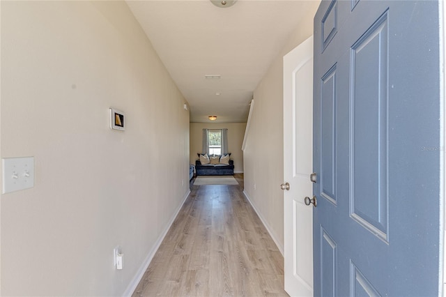 corridor featuring baseboards and light wood finished floors