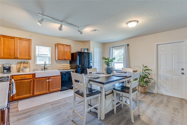 kitchen featuring a textured ceiling, black appliances, sink, and light hardwood / wood-style flooring