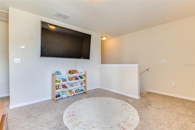 playroom with light carpet and a textured ceiling