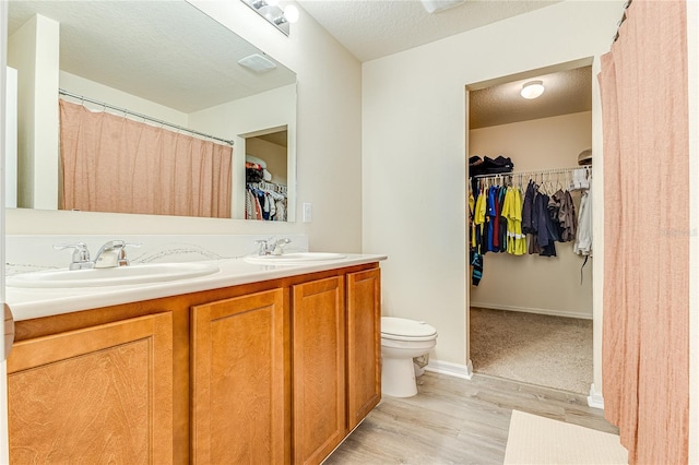 bathroom featuring a textured ceiling, vanity, toilet, and hardwood / wood-style flooring