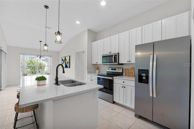 kitchen featuring white cabinets, vaulted ceiling, appliances with stainless steel finishes, sink, and an island with sink