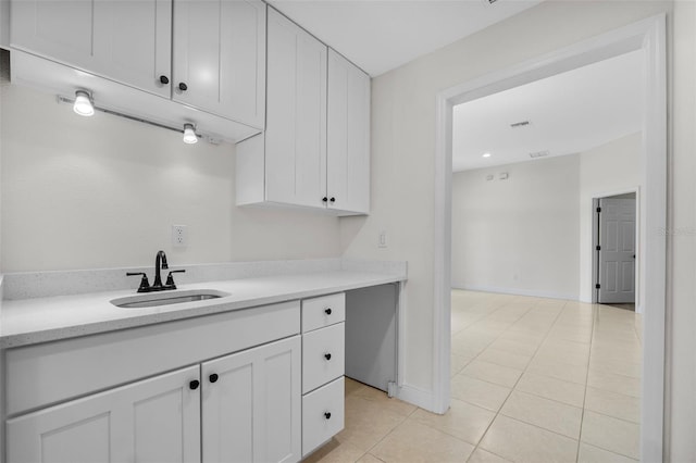 kitchen with light tile patterned flooring, sink, and white cabinets